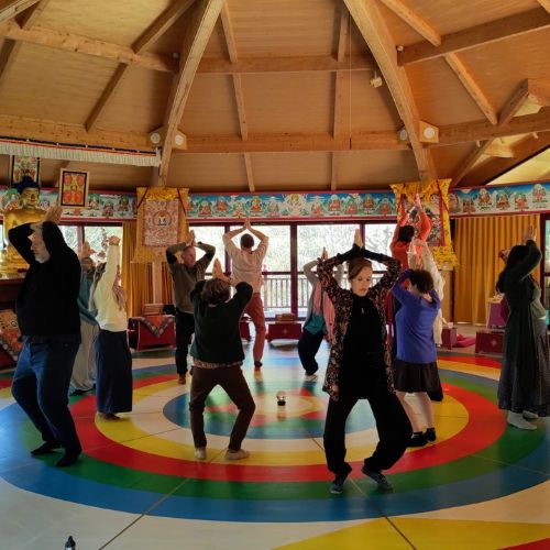 Pratiquants bras levés sur le mandala coloré de la Danse du Vajra dans le temple de Nigu Karma Ling